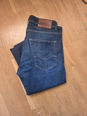 Mörkblå Replay jeans herr - Snygga mörkblå jeans från Replay med klassisk femficksmodell och diskreta slitningar framtill. Jeansen har raka ben och detaljer i kontrastsömmar samt Replay-lapp i läder bak i midjan. Perfekta till vardagslooken.