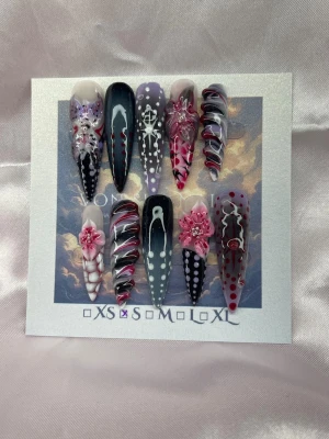 Botanica (S);ExtraLongStiletto  - Set unika handgjorda extra långa, spetsiga stiletto press-on naglar i svart, lila, vitt och rött med detaljer som prickar, swirl-mönster och 3D-blommor. Naglarna har en mix coola handmålade motiv för extra effekt.S: 15 mm, 11,5 mm, 12 mm, 11 mm, 9 mm 