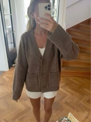 Brun Wera cardigan  - Mysig brun kofta i oversized modell med djup V-ringning och stora ribbade muddar. Koftan har två framfickor och stängs med tre knappar framtill. Lite små nopprig och ett litet hål på baksidan men utöver det är den i fint skick. Perfekt att slänga över en enkel outfit för en chill look. Tar emot bud 💞