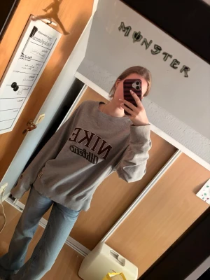 Grå sweatshirt från Nike Off-Field - Säljer en oversized grå sweatshirt från Nike Off-Field med stor vinröd och svart logga på bröstet. Tröjan har rund halsringning, ribbade muddar och en avslappnad passform. Köpte den secondhand men den kom aldrig till användning! Den har ingen lapp men skulle gissa att den är i storlek M/L! 