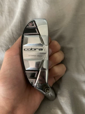 Cobra Hybrid Iron golfklubbhuvud - Säljer ett Cobra Hybrid Iron golfklubbhuvud i silver och svart. Huvudet har en modern design med geometriska detaljer och tydlig Cobra-logga. Passar dig som vill bygga eller byta ut delar på din golfklubba.