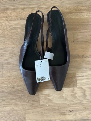 Bruna slingback pumps med låg klack - Bruna Slingbackklackar som aldrig är använda. Prislappen sitter kvar. Storlek 39