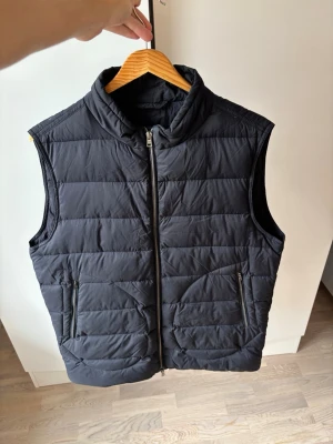 Helt ny Herno dunväst 50  - Jättefin blå tunn Herno dunväst av högsta kvalité från Herno i storlek M säljes. Västen har inga som helst defekter utan är i superfint nyskick! Grym passform och perfekt nu till hösten! Tveka inte vid minsta fråga eller fundering!