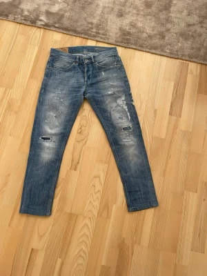 Blå Dondup jeans med raka ben  - Säljer ett par blå Dondup jeans med raka ben och slitna detaljer framtill. Jeansen har klassisk femficksdesign och är tillverkade i denim. Perfekta för en avslappnad och trendig look. W32, passform George skinnyfit