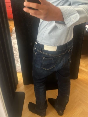 Mörkblå Replay jeans  - Ett par Schyssta mörkblå jeans från Replay, med luzien som modell men som passar mer som en slim fit modell. Tillverkade i stretchigt denim för extra komfort och passform. Jag är cirka 176 lång på bilden. Samt säljer då jag har bytt stil nära in på nyskick. Tveka inte på att ställa frågor!