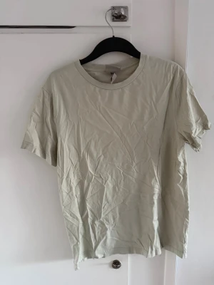 Mint grön basic t-shirt i bomull - En enkel och stilren beige t-shirt med rund hals och korta ärmar. Tillverkad i mjuk bomull som känns skön mot huden. Perfekt att matcha med jeans eller shorts för en clean look.