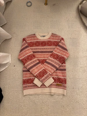 Mönstrad stickad tröja från Icewear - Stickad tröja från Icewear i vitt, rött och rosa med klassiskt nordiskt mönster. Tröjan har rund halsringning, ribbade muddar och är perfekt för kalla dagar. Materialet känns mjukt och värmande, och designen är riktigt snygg och trendig. Den är nyskick och oanvänd från Island med ull och angora💗 perfekt inför vintern