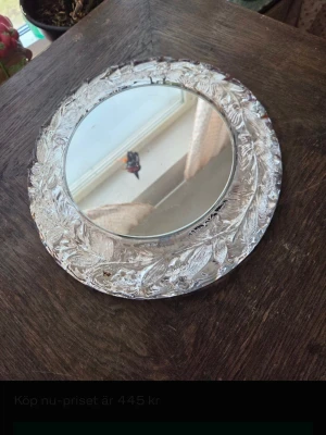 Rund spegel med glasram Skruf - Säljer en rund spegel med dekorativ glasram från Skruf. Ramen har ett vackert bladmönster i klart glas som ger en elegant och unik känsla. Perfekt som inredningsdetalj för att skapa en stilren look i rummet. Obs ! Tung!