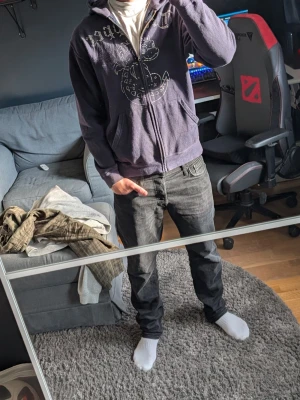Mörklila hoodie med dragkedja från trapper - Säljer en mörklila hoodie med dragkedja och tryckt motiv på bröstet. Hoodien har huva och är tillverkad i mjukt material, perfekt för en avslappnad stil. Passar dig som gillar streetwear och vill ha något bekvämt och snyggt. Den är andvända men sitter bra. Hör av dig fråga 