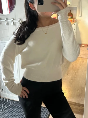 Vit stickad tröja  - Säljer en vit stickad tröja med bred ribbad mudd i midjan och vid ärmsluten. Man kan välja om man vill ha den off shoulder! Obs den är lite smutsig vid slutet på ena ärmen samt lite nopprig men annars i bra skick!  🥰🥰✨🌸 