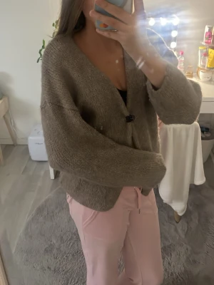 Beige stickad kofta öppen modell - Mysig beige stickad kofta i öppen modell utan knappar. Koftan har långa ärmar och är gjord i ett mjukt, lite grovt garn. Perfekt att slänga över en t-shirt eller topp för extra värme. Enkel och stilren design som passar till det mesta.