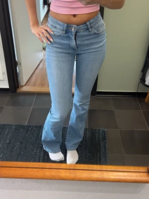 Ljusblå bootcut jeans - Snygga ljusblå jeans med bootcut passform och klassisk femficksdesign. Jeansen har hög midja och stängs med knapp och dragkedja. Perfekta för en avslappnad och trendig look. Xs längd 30 