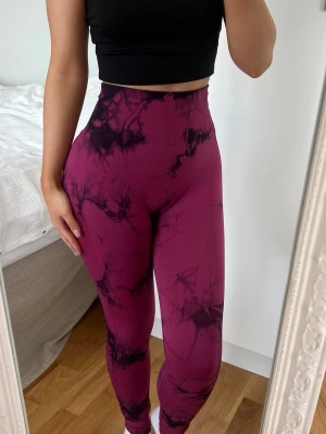 Träningstights  - Snygga vinröda / rosa träningstights med scrunch, tie-dye mönster och hög midja. Tightsen är sömlösa och sitter tight, perfekta för gymmet eller yoga. Materialet är stretchigt och följsamt för maximal rörelsefrihet. Storlek XS i bra skick 🩷