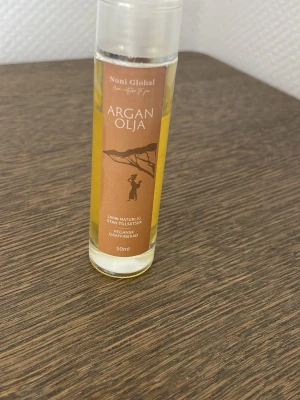 Arganolja 50ml från Nuni Global - Arganolja från Nuni Global i en genomskinlig plastflaska med brun etikett. Innehåller 50ml, 100% naturlig, utan tillsatser, vegansk och oraffinerad. Perfekt för hud och hår, ger näring och glans.