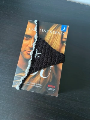 Svart virkat bokmärke  - Ett bokmärke i form av en trosa med spetskant och en liten rosett framtill 