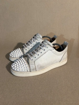 Christian Louboutin Louis Junior - Storlek: 41 EU = 7/7,5 UK | Färg: Vit | Skick: Okej skick | Defekter: Slitage på lädret, vissa spikar är slitna och ytter sulan är sliten | Material: Läder | Tillbehör: Inget | Pris: 2299kr | Dm för frågor.