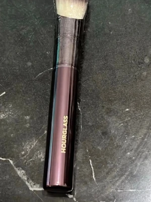 Hourglass sminkborste vinklad - Lyxig sminkborste från Hourglass med vinklad borst och mörklila metallhandtag. Borsten har täta, mjuka syntetiska strån som passar perfekt för contouring eller applicering av foundation.