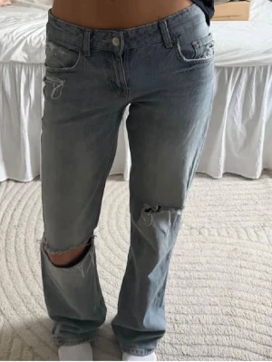 Ljusblå jeans från zara - Ljusblå jeans från Zara med raka ben och slitningar vid knä och fickor. Jeansen har klassisk femficksdesign och är tillverkade i denim. säljer eftersom de ej kommer till användning 💗
