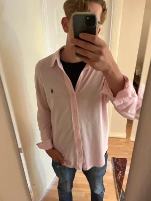 Ljusrosa skjorta från Ralph Lauren - Klassisk ljusrosa skjorta från Ralph Lauren tillverkad o featherweight mesh! Skjortan är väl omhändertagen och passar perfekt att både ha som vanligt eller att använda som lager på lager! Skjortan är i stl m men skulle säga att den passar mer som en L. Tveka inte vid att höra av vid funderingar. 