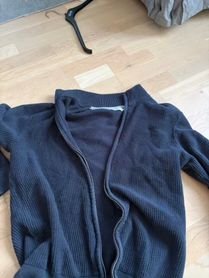 Mörkblå ribbad ziptröja East West - Mörkblå ribbad ziptröja från East West med hög krage och dragkedja framtill. Tröjan har en enkel och stilren design, perfekt för lager på lager och passar till det mesta. Materialet är mjukt och bekvämt.
