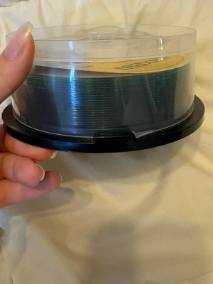 Maxell CD-R 25-pack spindel - Säljer en spindel med 25 stycken Maxell CD-R skivor. Varje skiva rymmer 700 MB eller 80 minuter och har en maxhastighet på 52x. Förpackningen är rund med genomskinligt lock och svart botten, perfekt för lagring av musik, filer eller backup.