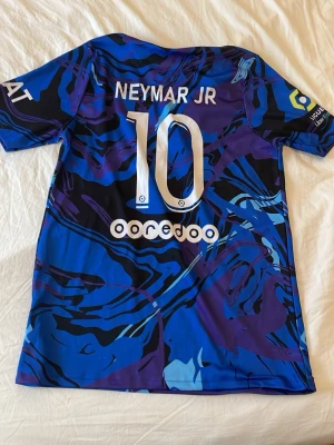 Limited PSG Neymar JR blå/lila matchtröja - Säljer en PSG matchtröja med Neymar JR och nummer 10 på ryggen. Den är storlek 176/S, den passar som S. Den har ett ställe där bak på ryggen där den är lite nopprig men det syns bara vid nära inspektion, inget man lägger märke till vid användning. Hör av dig vid frågor!! Pris kan diskuteras!!