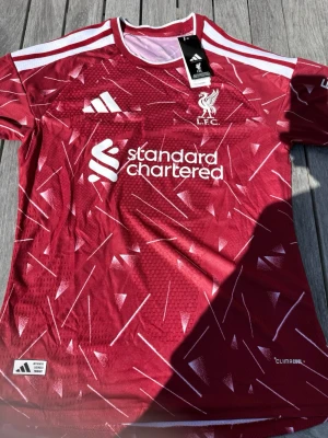 Szoboszlai #8 – Hemma Liverpool (storlek M) - Szoboszlai #8-tryck. Nya säsongens hemmatröja. Storlek M. Helt ny och aldrig använd. Skickas snabbt 🚚💨  Mått (M): Halvt bröstmått 51 cm • Längd 72,5 cm • Ärmbredd 22,5 cm • Axelbredd 43 cm • Ärmlängd 39 cm • Manschett 18 cm.  🔥 Player Edition – tajtare passform än vanliga supportertröjor.  📩 Skicka gärna ett meddelande vid frågor eller prisförslag! 🛍 Bundle-rabatt upp till 20%! 📦 Skickas samma eller nästa dag.