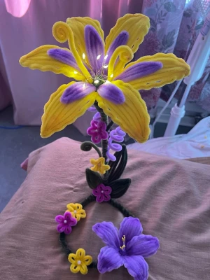 Färgglad blomsterdekoration med LED - Unik handgjord blomsterdekoration i gult, lila och grönt med stora sammetslena blommor och små LED-lampor i mitten. Blommorna är formade av mjuka piprensare och dekorationen passar perfekt som accessoar till rummet eller som kreativ detalj till din stil.