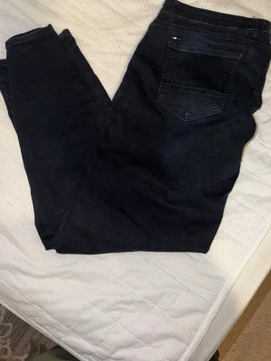 Mörkblå slim fit jeans - Snygga mörkblå jeans i slim fit-modell med klassisk femficksdesign. Jeansen har en diskret detalj på bakfickan och är tillverkade i ett mjukt denimtyg som ger en bekväm känsla. Perfekta för dig som gillar en stilren och enkel look.