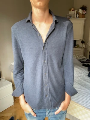Mörkblå långärmad Ralph lauren skjorta - Säljer en stilren mörkblå skjorta med långa ärmar och knappar framtill. Skjortan har klassisk krage och är tillverkad i ett mjukt bomullsliknande material. Perfekt för en avslappnad men ändå snygg look.