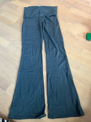 Grön/grå utsvängda yogapants Gina Tricot - Grön/grå yogapants från Gina Tricot i storlek S. Modellen har hög midja och utsvängda ben, vilket ger en trendig siluett. Mjukt och stretchigt material som sitter skönt på kroppen. 