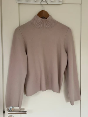 Beige stickad polotröja från Object - Snygg beige stickad polotröja från Object i storlek XS. Tröjan har en hög ribbad krage och långa ärmar. Materialet känns mjukt och passar perfekt till kyligare dagar. Enkel och stilren design som är lätt att matcha.