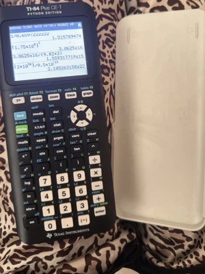 TI-84 Plus CE-T Python Edition miniräknare - En svart och vit grafritande miniräknare från Texas Instruments, modell TI-84 Plus CE-T Python Edition. Har stor display, många funktionsknappar och medföljande vitt skyddsfodral i plast. Perfekt för matte, programmering och naturvetenskap.