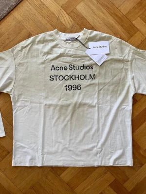 Vit Acne Studios long sleeve t-shirt med tryck. - Vit long sleeve t-shirt från Acne Studios med svart texttryck 'STOCKHOLM 1996' på framsidan. Klassisk rund hals och långa ärmar. Perfekt för en clean och modern stil.                      Fraktar inom 24h🚚💨.                                        Det är bara att höra av dig vid frågor!🙋‍♂️