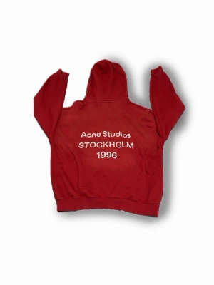Röd hoodie Acne Studios Stockholm - Snygg röd hoodie från Acne Studios med trycket 'Acne Studios STOCKHOLM 1996' Storlek M sitter som en M men värt att tänka på är att den inte sitter lika slim som en vanlig hoodie! Fråga om bilder när den är på om ni vill!