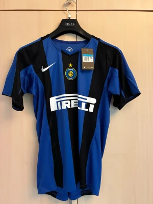Nike Inter Milan  - Säljer en blå och svart randig matchtröja från Inter med Nike-logga och Pirelli-tryck på bröstet. Tröjan har klubbmärke med stjärna, korta ärmar och är tillverkad i ett lätt, ventilerande material perfekt för fotboll eller träning. 