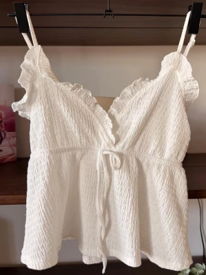 Vit volang topp - Otroligt söt topp med volang detaljer som dessutom sitter mer som en magtröja i längden. Denna är och har varit en stor favorit! (Har två) Passat till allt: mjukis, jeans, kjol till och med bikini!                                                  ⭐️Säljes i använt skick, utan defekter & slitage. Väl omhändertagen                                                                             💭Har du frågor? Skriv på annonsen och jag svarar så fort jag kan!