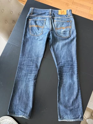 Nudie jeans Bootcut Ola  - Säljer ett par schyssta nudie jeans i modellen Bootcut Ola med riktigt snygga slitningar | Jeansen slutade tillverkas 2012 och är därför väldigt eftertraktade | Sjukt snygg passform | Midja: 42cm, Ytterbenslängd: 101cm, Benöppning 21cm (Ta måtten med +/- nån cm) | Hör av dig vid minsta fundering