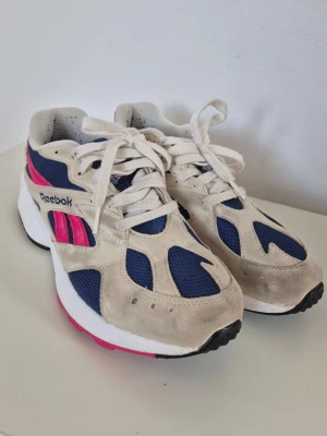 Reebok Aztrek OG (Chalk/Bright Rose/Collegiate Royal) - Reebok Aztrek OG (Chalk/Bright Rose/Collegiate Royal)   Retro-modell i off-white, marinblå och rosa.  De är i fint skick, har ej använt de mycket, se bilderna på undersidan. Bara mockan som behöver rengöras lite och nopprigt där inne pga svarta strumpor (jag vet 😑).  Storlek: inköpta 37,5 men passar mig som annars har 38. Innermått 24,5 cm.
