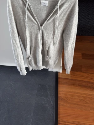 Ljusgrå cashmere hoodie John Henric - Mjuk och stilren ljusgrå hoodie från John Henric i 100% cashmere. Hoodien har dragkedja framtill, två fickor och justerbar huva med snören. Perfekt för dig som vill ha en lyxig och bekväm look. Kan byta mot en sån i mörkblå också