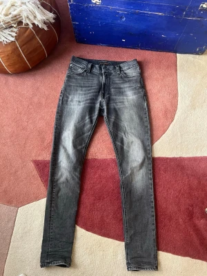 Grå nudie jeans ”grey ring”  - Säljer ett par grå slim fit jeans med snygga slitningar och tvättade detaljer. Jeansen har klassisk femficksmodell, normal midja. Perfekta för en avslappnad och trendig look.