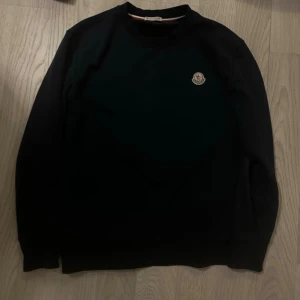 Moncler sweatshirt  - Stilren svart sweatshirt från Moncler med rund halsringning och klassisk Moncler-logga på bröstet. Tröjan har långa ärmar och en enkel, clean design som passar perfekt till jeans eller joggers.