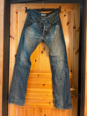 Vintage Acne jeans - Säljer ett par riktigt schyssta vintagejeans från Acne Jeans, tillverkade runt 2005–2006. Detta är ett tidigt arkivplagg i 100 % kraftig bomullsdenim (ingen stretch) från tiden innan märket bytte namn till Acne Studios. Mått finns! Gott vintageskick med mycket karaktär. OBS! Jeansens har en kraftig, rejäl och tät sicksack-lagning (stoppning) i grenen (se bilder). Det gör tyget helt stabilt och slitstarkt igen, men ger också byxorna en cool, rå "distressed" workwear-look. Original-läderpatche