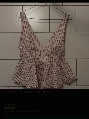Randig ärmlös topp Zara helt ny! - Söt ärmlös topp med djup v-ringning och volang nedtill. Toppen är vit med röda och gröna ränder samt små körsbärsmönster. Den har breda axelband och smock i midjan för en bekväm passform. Dragkedja i sidan. Perfekt för varma dagar! Storlek 