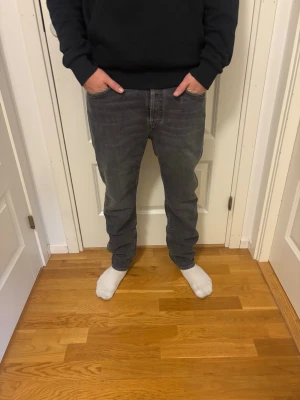 Grå raka jeans - Säljer ett par grå jeans med rak passform och klassisk femficksdesign. Jeansen har normal midja och är tillverkade i ett mjukt denimtyg. Perfekta för en avslappnad och stilren look.