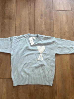 Helt ny Ami Paris Oversized Jumper (Ljusblå/Vit) - Strl S 🔥✨ - Säljer en superfresh och helt ny Ami Paris-tröja i en snygg ljusblå nyans med den klassiska stora Ami de Coeur-loggan i vit chenille. Aldrig använd, tags och originalpåse medföljer!  Storlek: S (Oversized fit)  Skick: Helt ny / Deadstock (DS) med tags  Färg: Ljusblå / Vit  Kvitto: Saknas Skickas spårbart eller hämtas enligt överenskommelse. Köparen står för frakten. Skriv ett DM om du har några frågor eller vill ha fler bilder! 👕✨ 