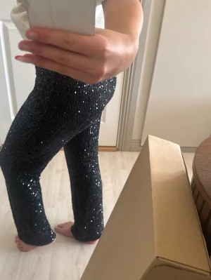 Svarta paljettbyxor - Glittriga svarta byxor med paljetter. Perfekta för dig som vill sticka ut och glänsa lite extra. Stretchigt material som sitter snyggt på kroppen.