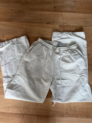 Beiga linnebyxor från Madlady - Säljer ett par beiga linnebyxor från Madlady i storlek XS. Byxorna har resårmidja med dragsko och raka ben. Tillverkade i ett luftigt linnematerial som passar perfekt för en avslappnad stil. Två sidofickor för extra chill vibe.