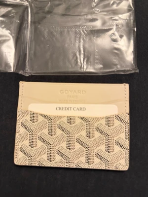 Beige kortfodral  - Snyggt och stilrent kortfodral i färgen beige med det klassiska mönstret. Fodralet har flera fack för kort och är tillverkat i ett tåligt material med lyxig känsla. Perfekt för dig som vill ha koll på dina kort med stil.