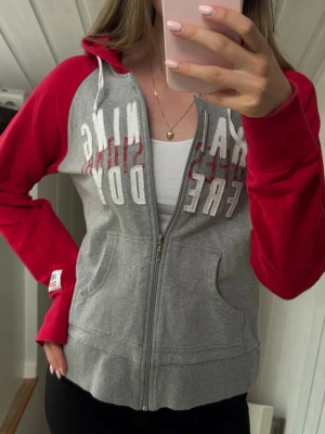 Grå och röd zip hoodie från Freddy Training - Zip-hoodie från Freddy Training i grått med röda ärmar och huva. 